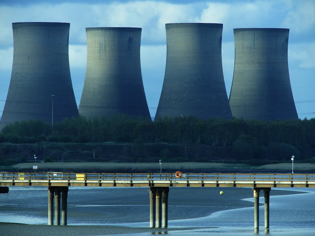 View of industrial cooling towers and a bridge over water, showcasing energy infrastructure.